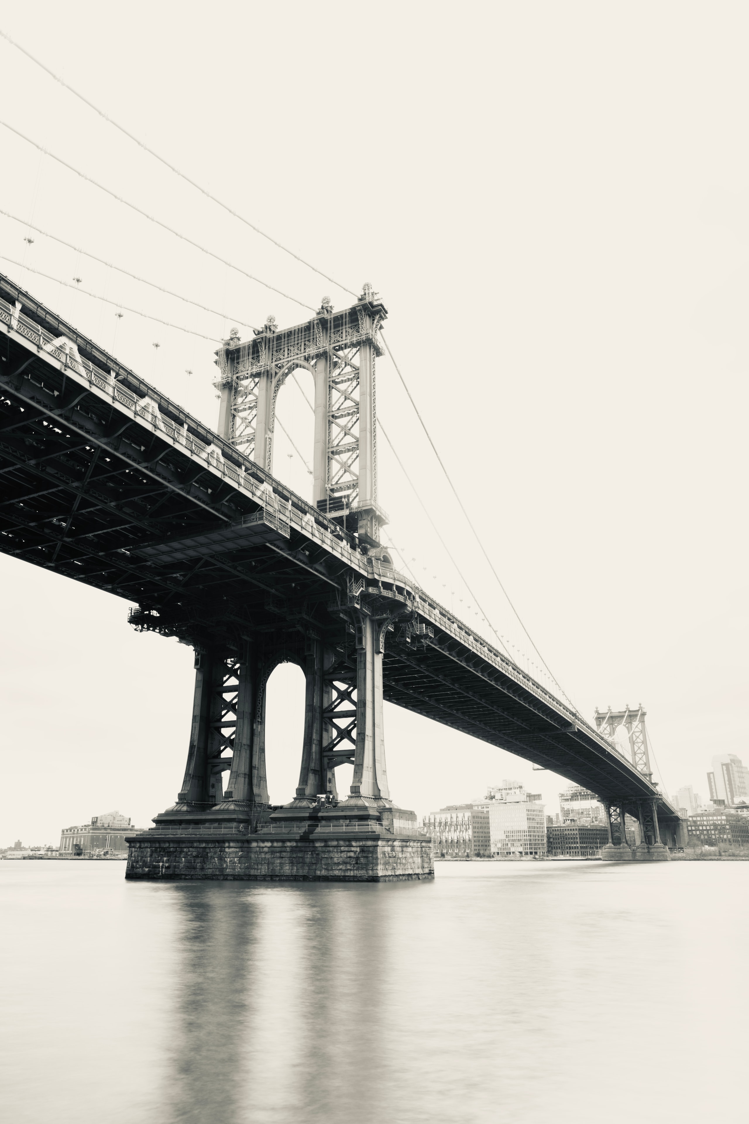 Manhattan Bridge massive steel towers and cables rising from the East River in soft grey tones