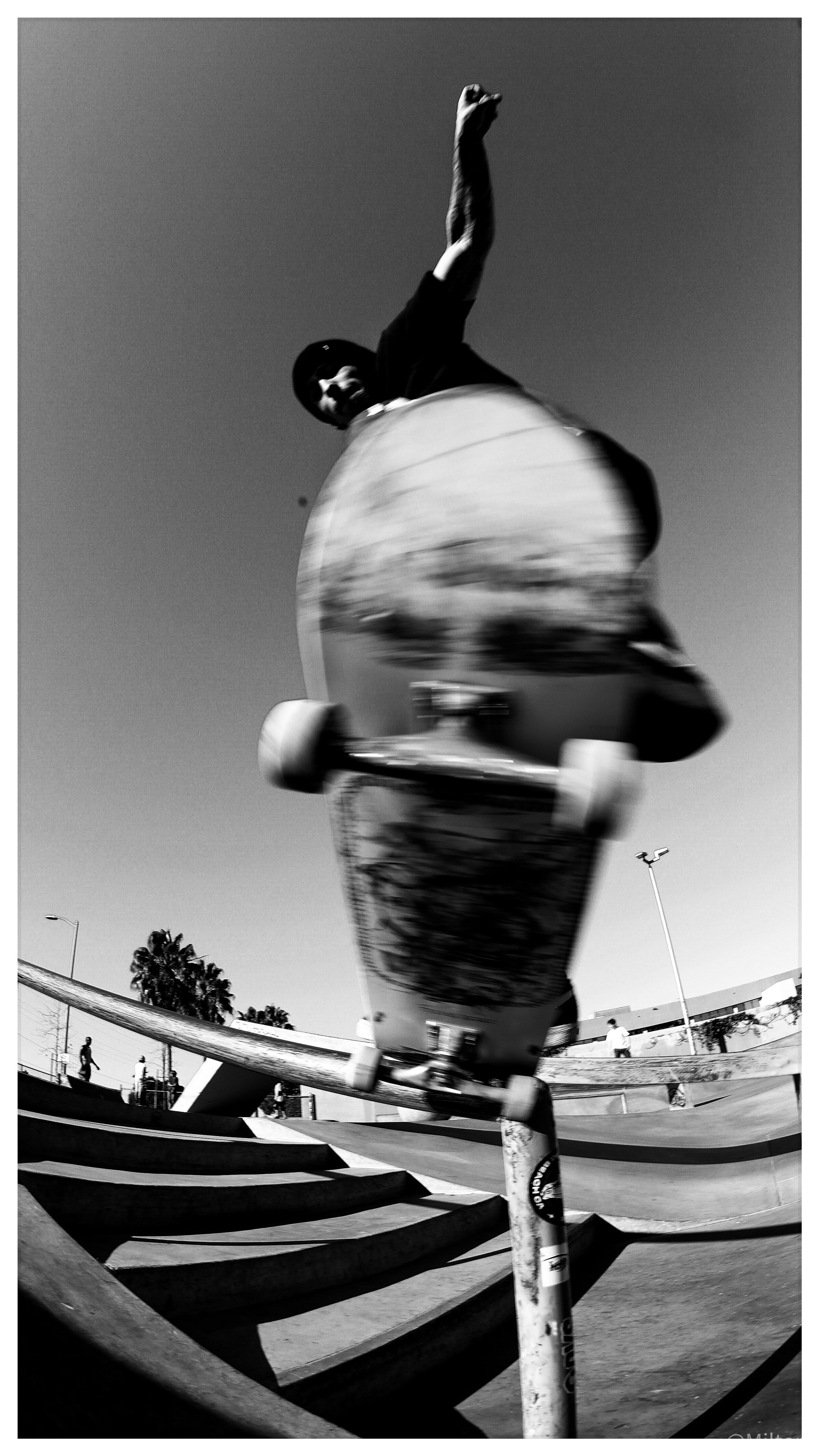 Dynamic fisheye action shot of skateboarder launching trick at Venice Beach skate park