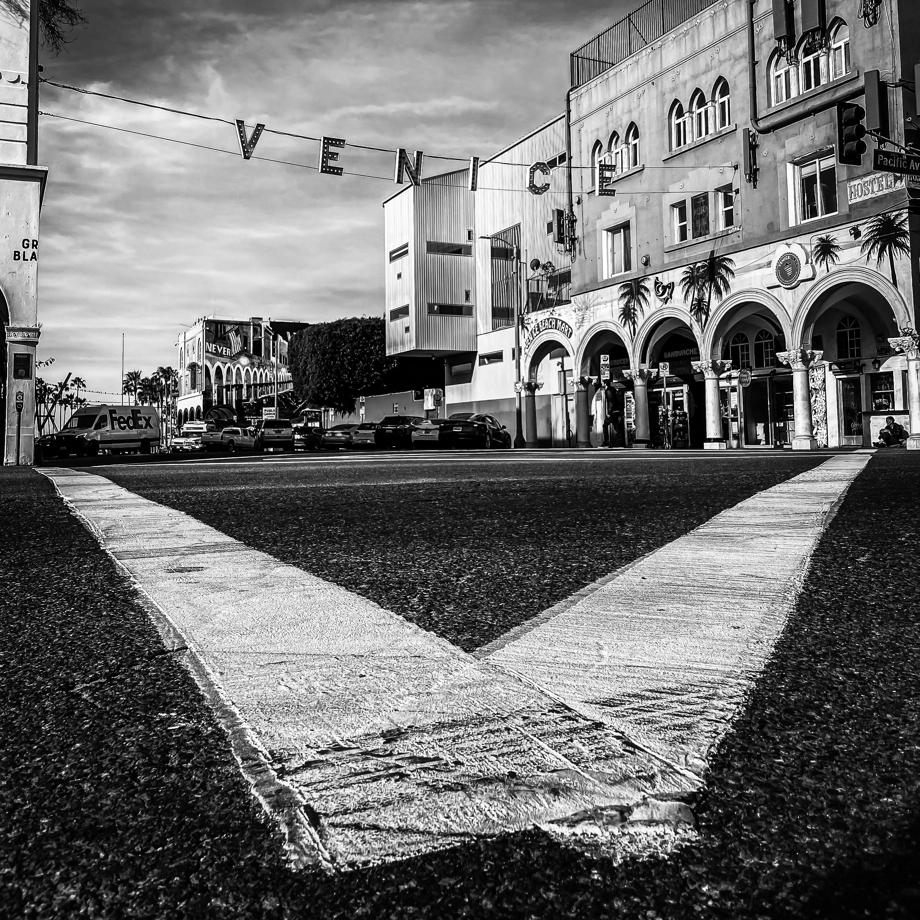 Low angle street view of Venice Beach intersection with VENICE sign strung overhead and historic buildings