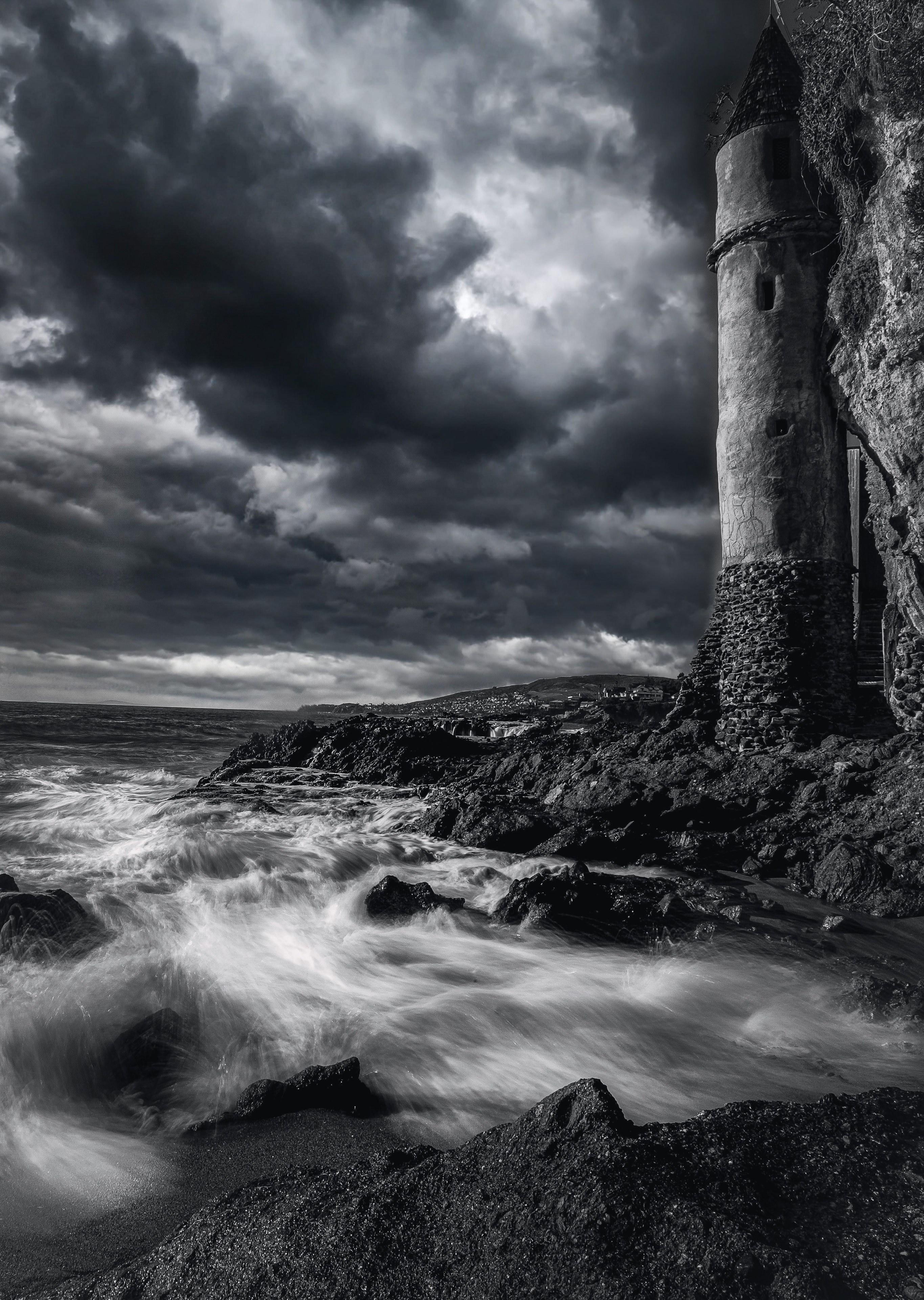 Ruined coastal tower with turbulent waves crashing on rocks under dramatic stormy sky