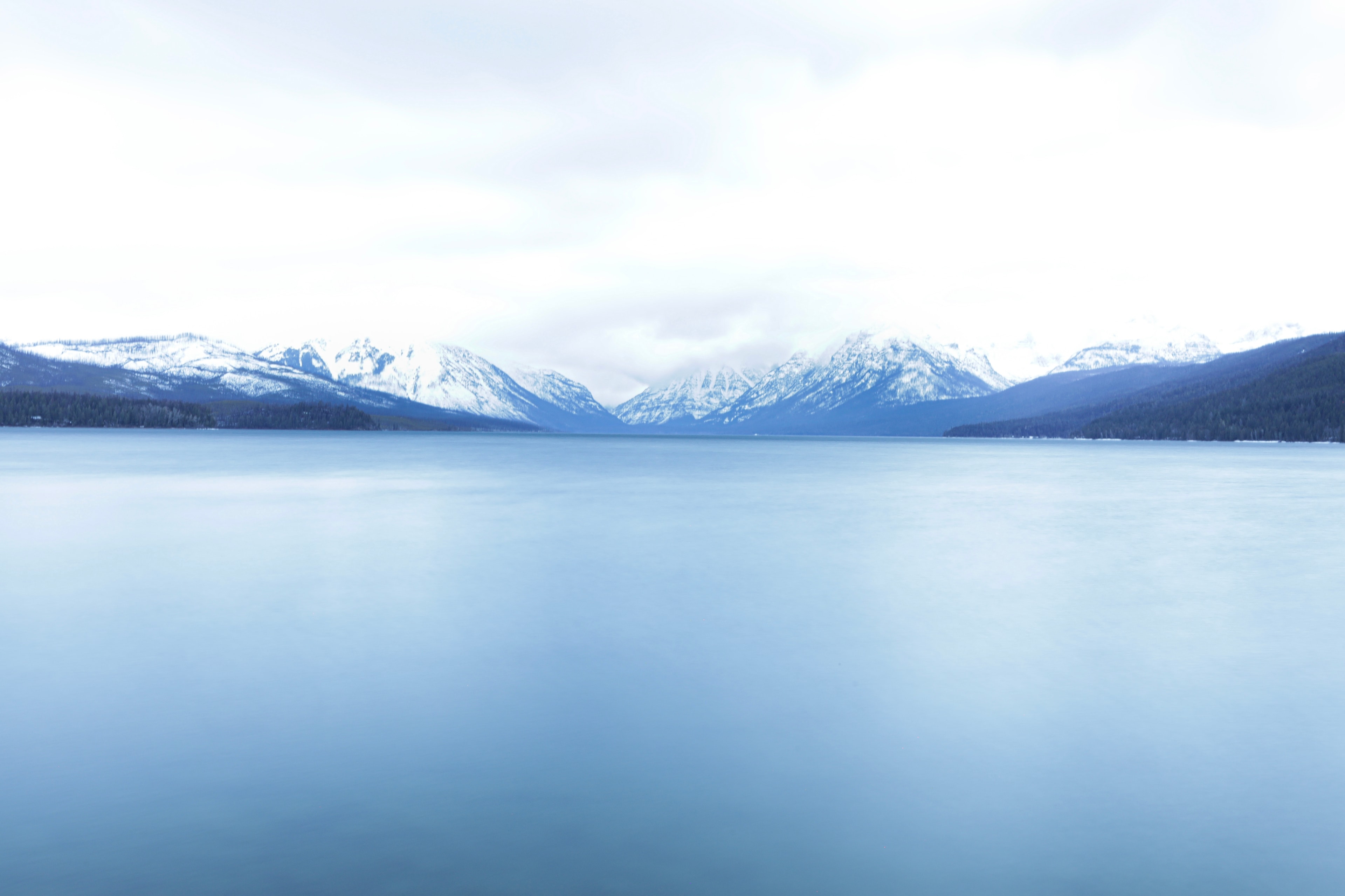 Serene mountain lake with snow-capped peaks under overcast winter sky