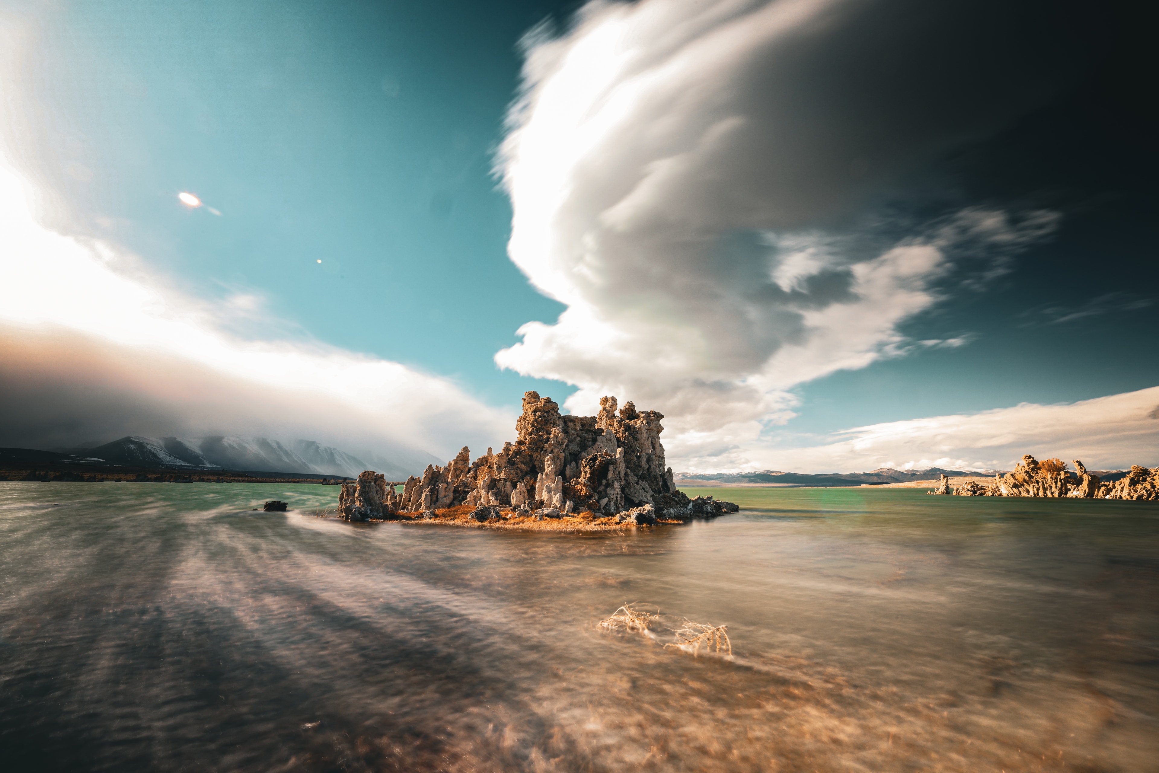 Mono Lake tufa towers rising from turquoise water under dramatic storm clouds with Sierra Nevada mountains in the background