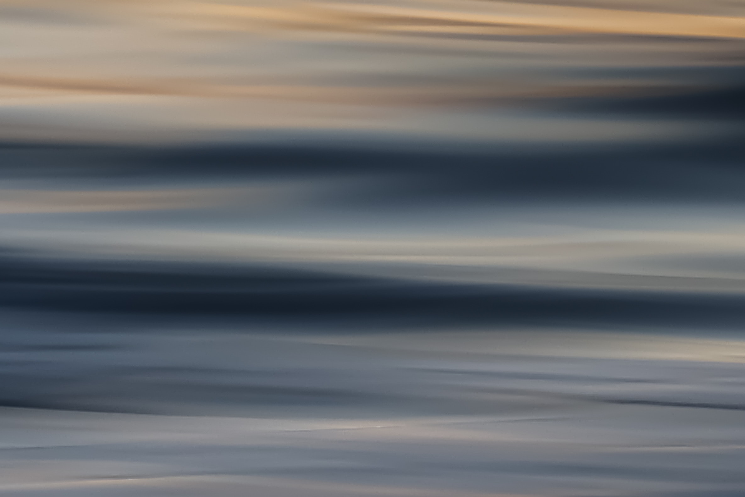 Abstract motion blur seascape with cool blue-grey tones and warm golden upper band