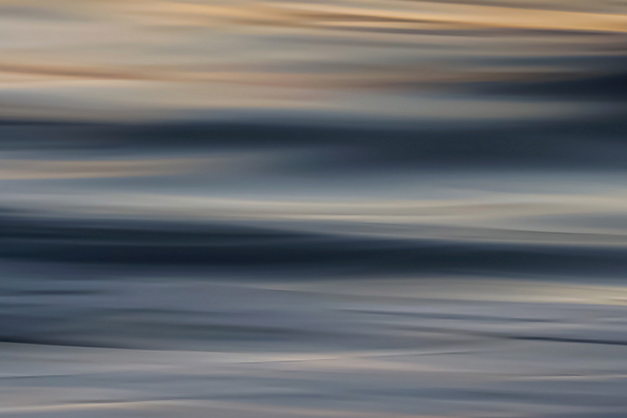 Dreamy abstract ocean blur with cool silver-blue tones and subtle warm highlights