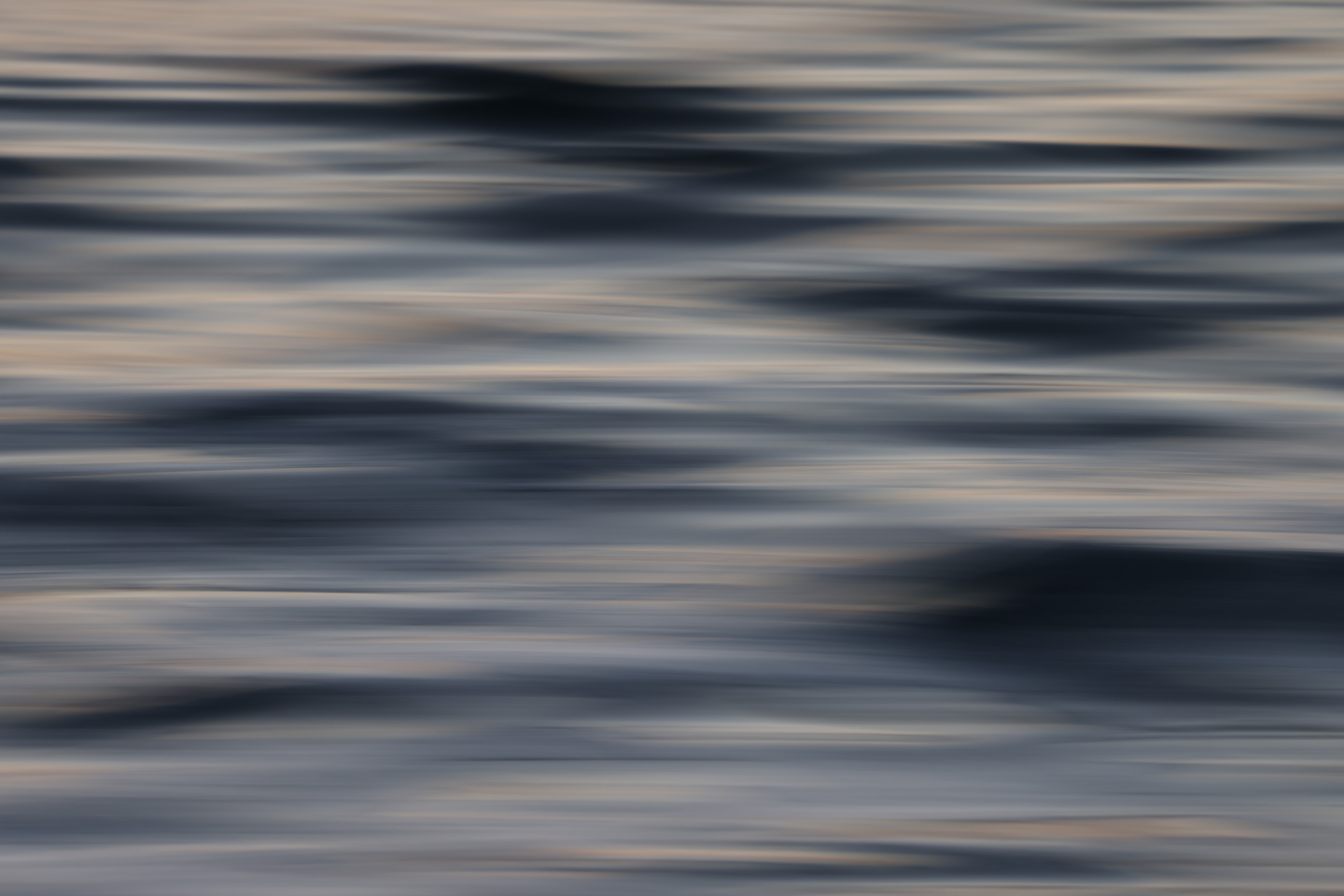 Abstract ocean motion blur with pale silver-blue tones and scattered warm golden streaks