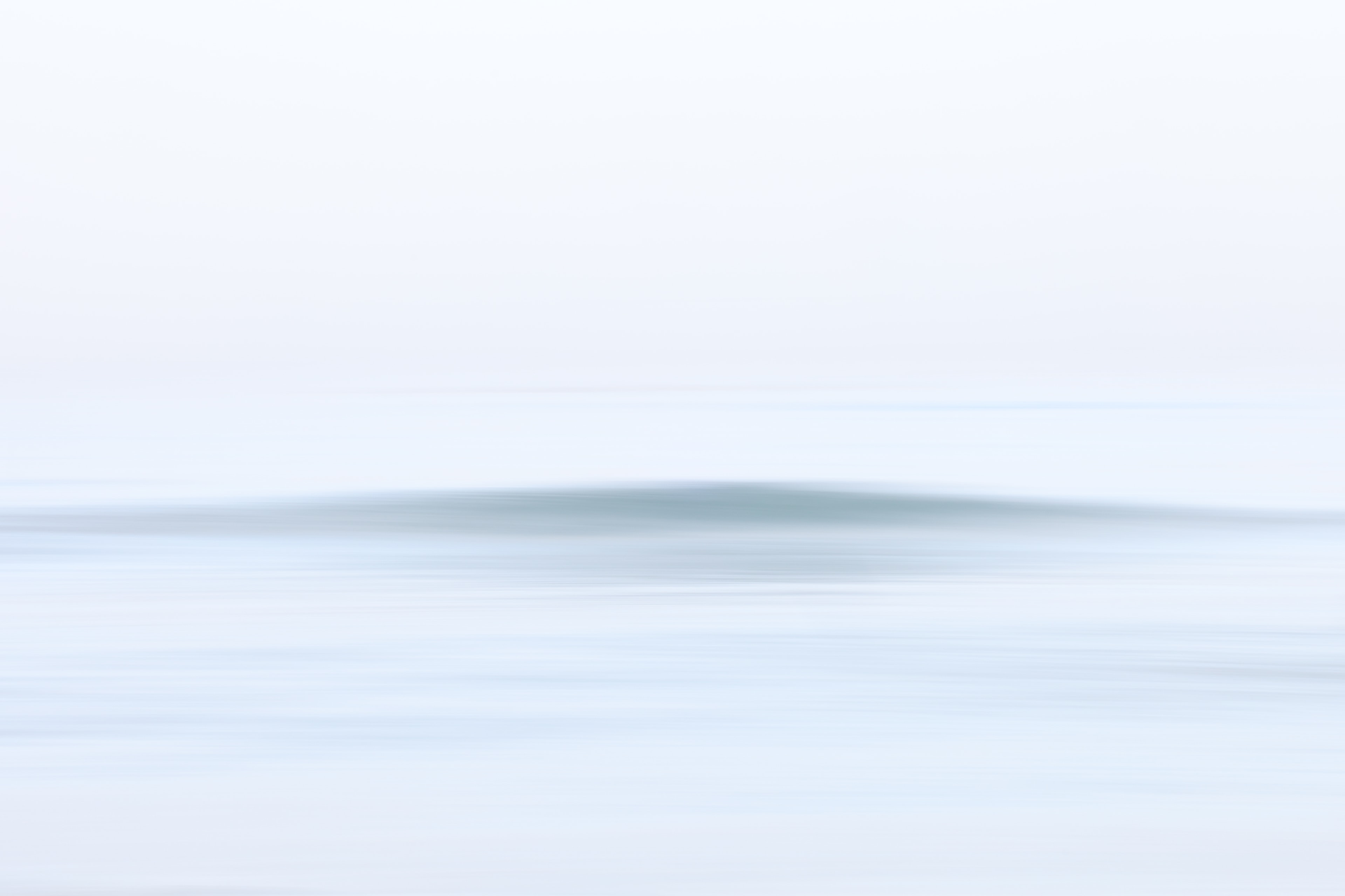 Minimalist seascape with a gentle wave form emerging from misty water
