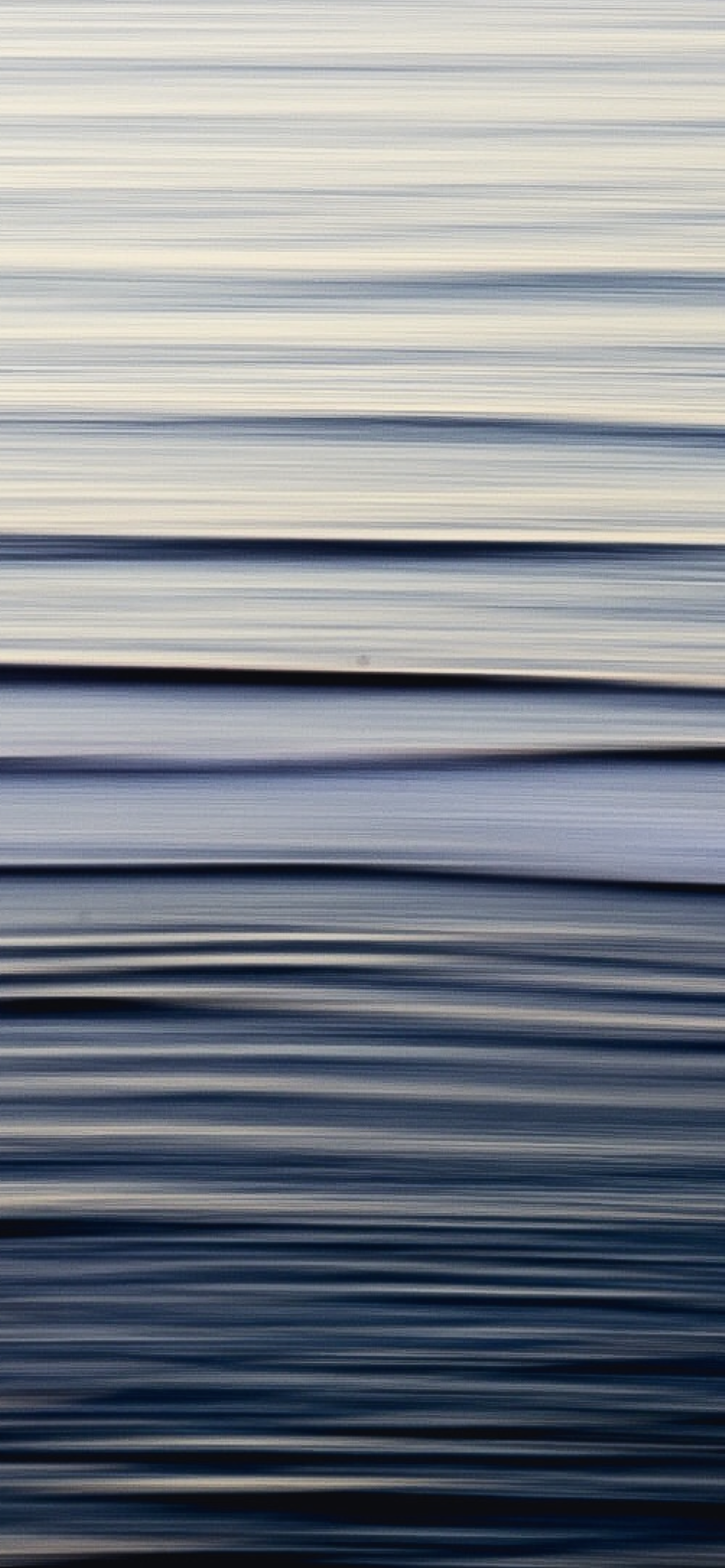 Abstract motion blur seascape with tall vertical composition of pale silver and deep indigo wave bands