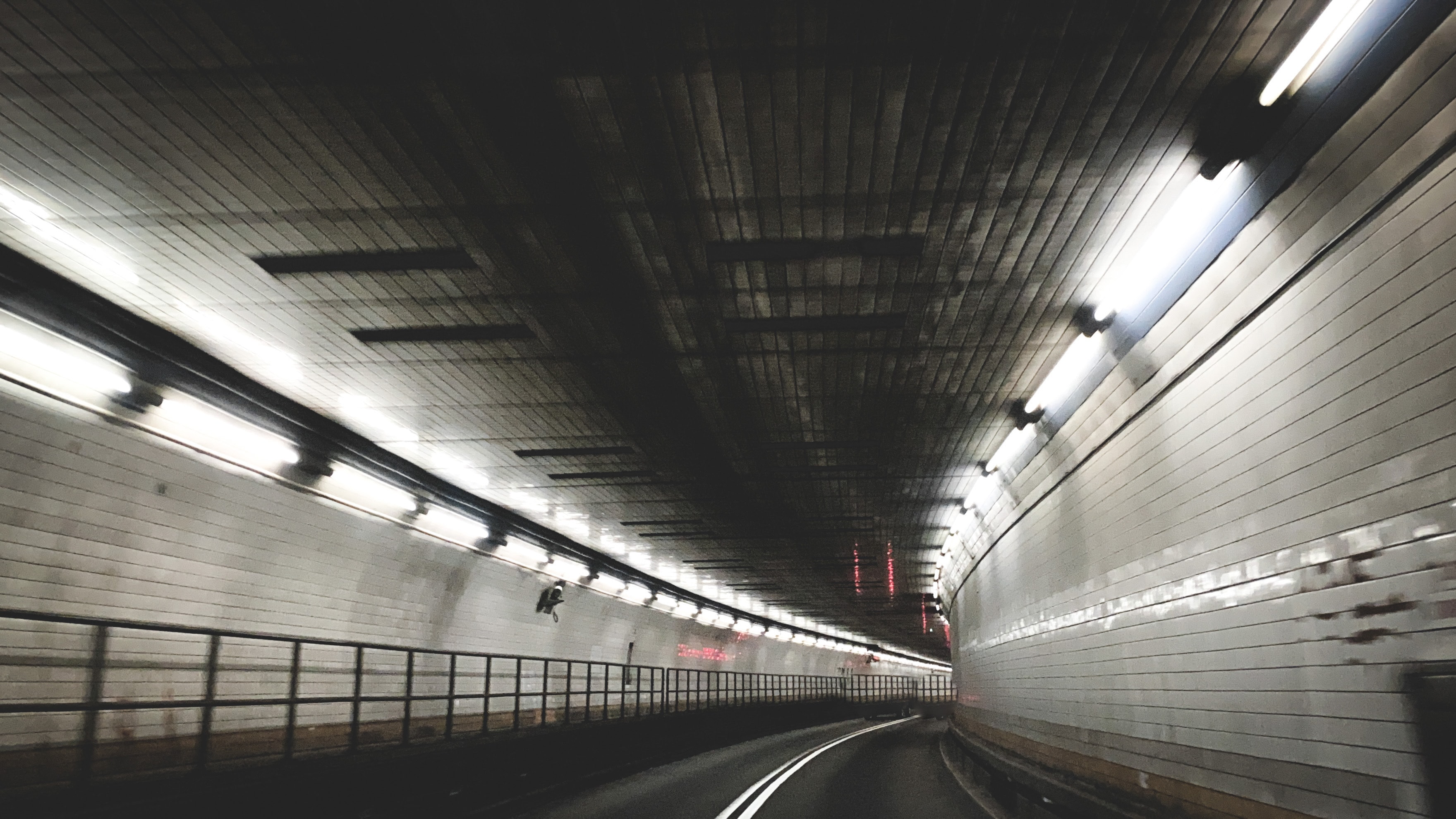Speeding through a curved tunnel with white tile walls and blurred fluorescent lights