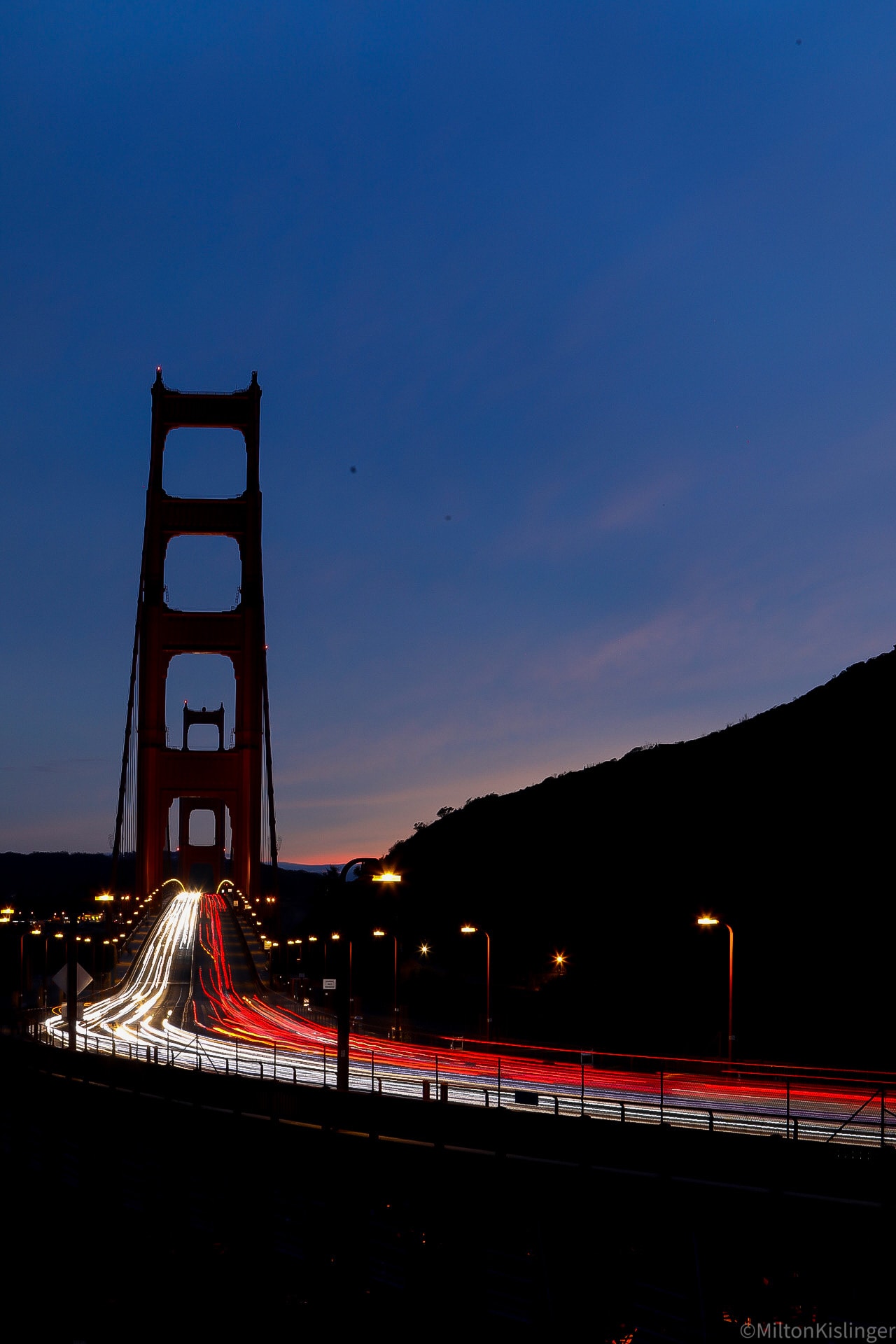 Golden Gate Bridge tower at dusk with long exposure light trails from traffic below